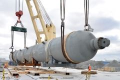 A large industrial vessel being lifted by a crane.