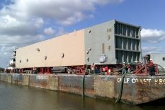 A massive beige rectangular structure, likely industrial equipment, on a barge, labeled 