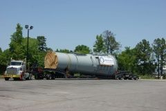 A large cylindrical tank on a flatbed truck, being transported on a road.