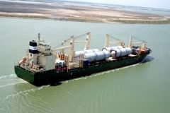 Cargo ship transporting large white cylindrical containers on water.