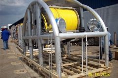 Large industrial spool of yellow cable on a metal frame, outside. Pallet base.