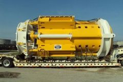 Yellow and white tunnel boring machine on a flatbed trailer, ready for transport.