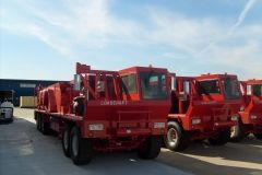 Red Combi trucks parked in a lot under a blue sky.