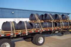 Steel pipes secured on pallets loaded on a flatbed truck, ready for transport.