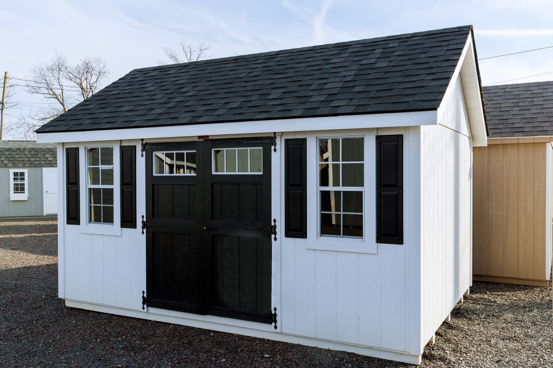 A white shed with black shutters and a black roof.