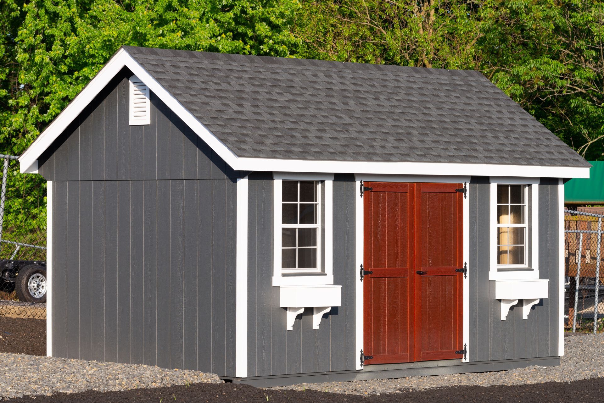 A gray shed with a red door and windows