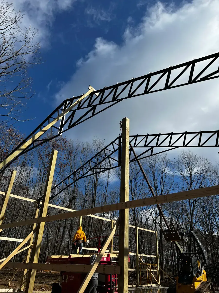 A large metal structure is being built in the woods.