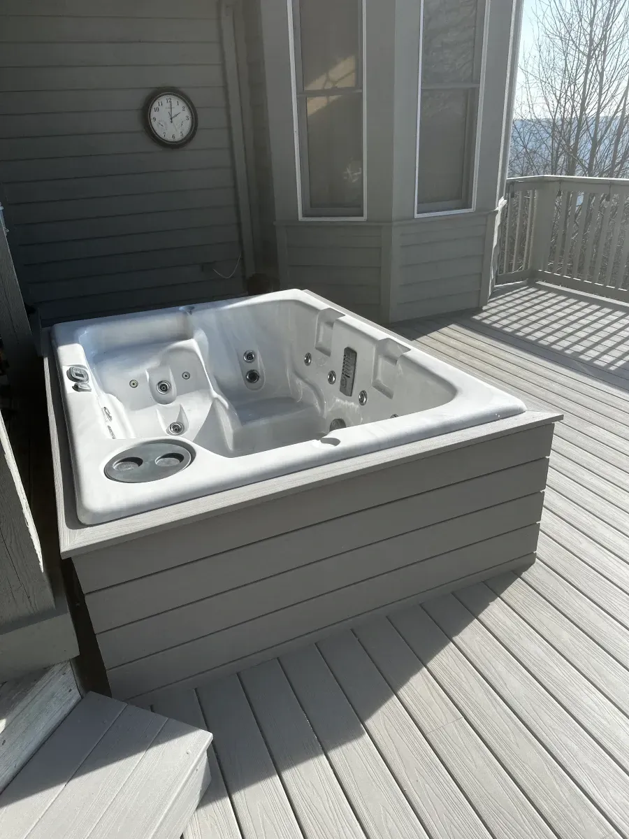 A hot tub is sitting on top of a wooden deck.