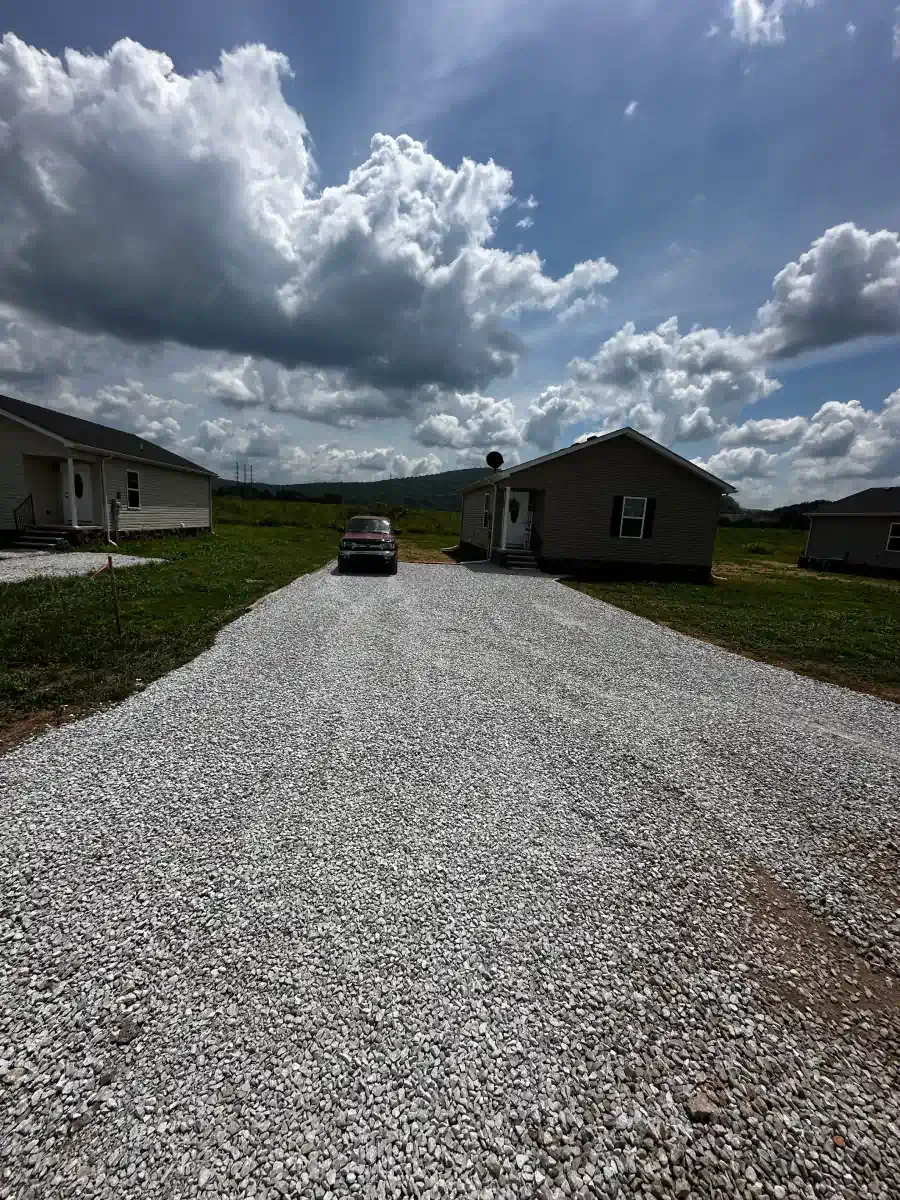 A gravel driveway leading to a house on a sunny day.