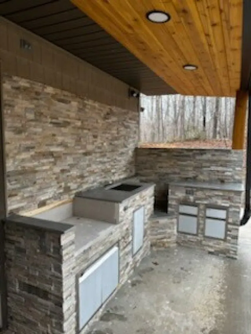 A kitchen with a stone wall and a wooden ceiling