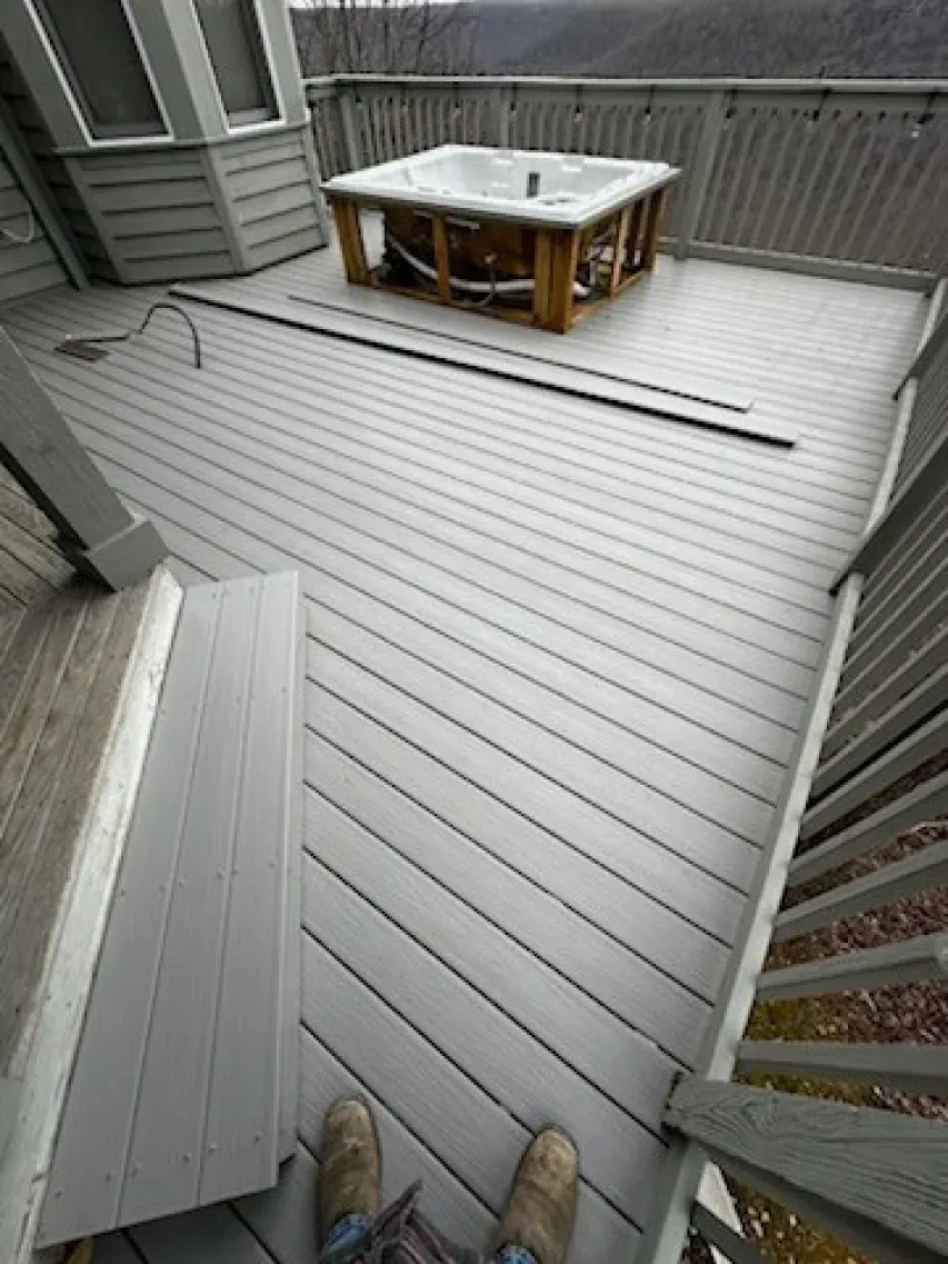 A person is standing on a deck next to a hot tub.