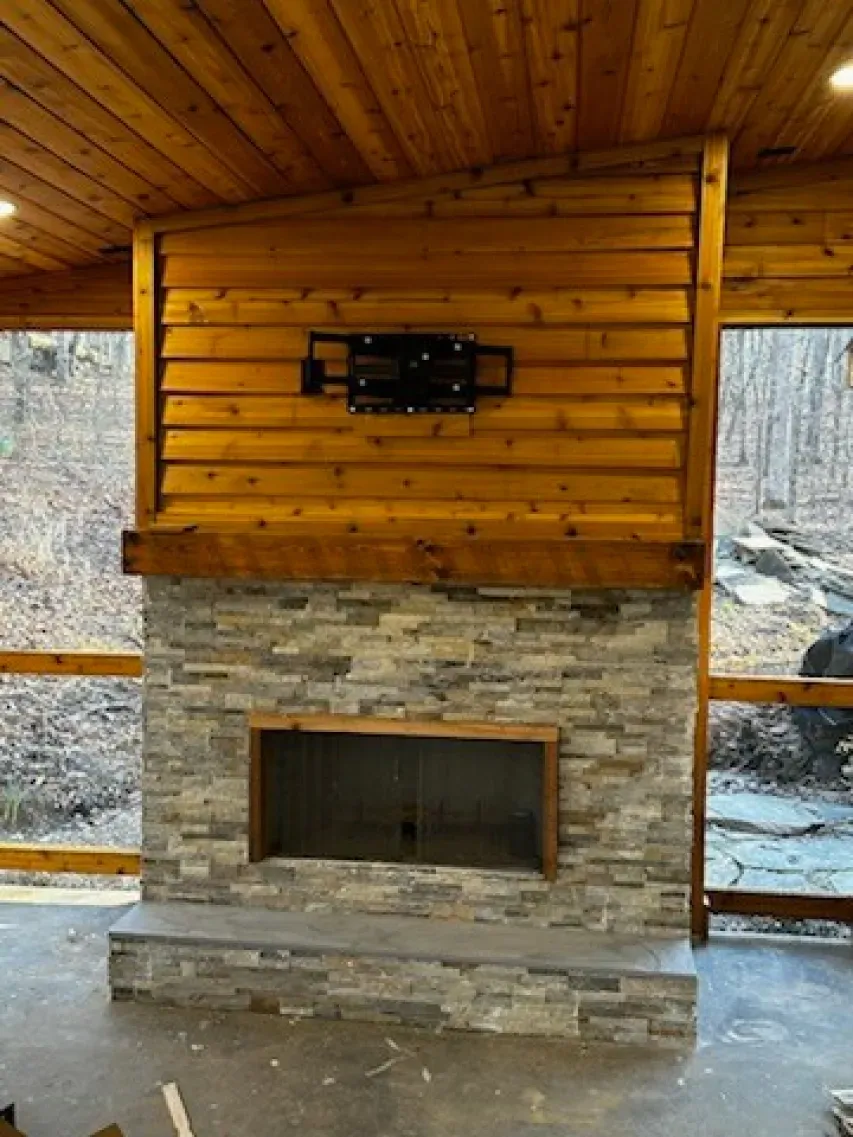 A stone fireplace with a flat screen tv mounted on the wall.