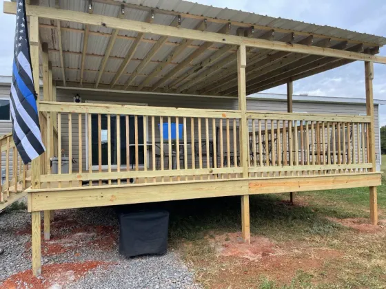 A mobile home with a wooden deck and a blue line flag.