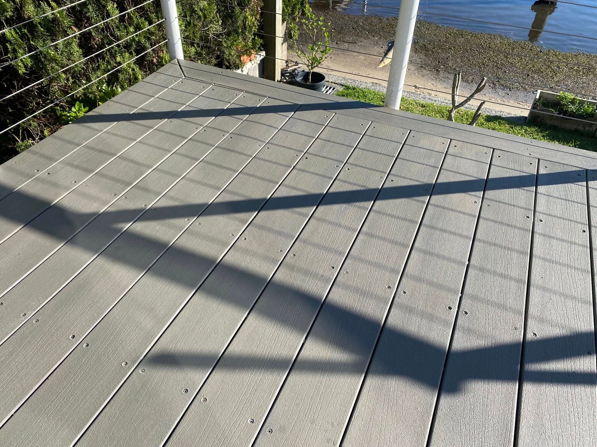 Gray composite deck with strong shadows, overlooking a body of water — Custom Floor Sanding In Somersby, NSW