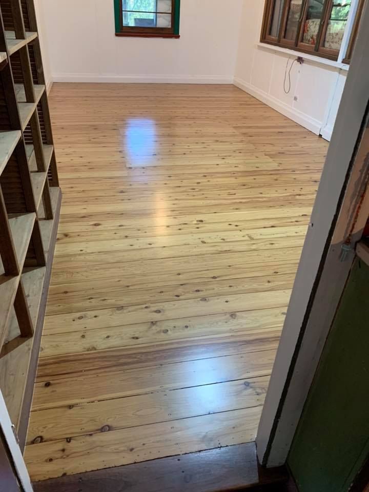 Wooden floor in a room with built-in shelves on the left and a window in the background — Custom Floor Sanding In Terrigal, NSW