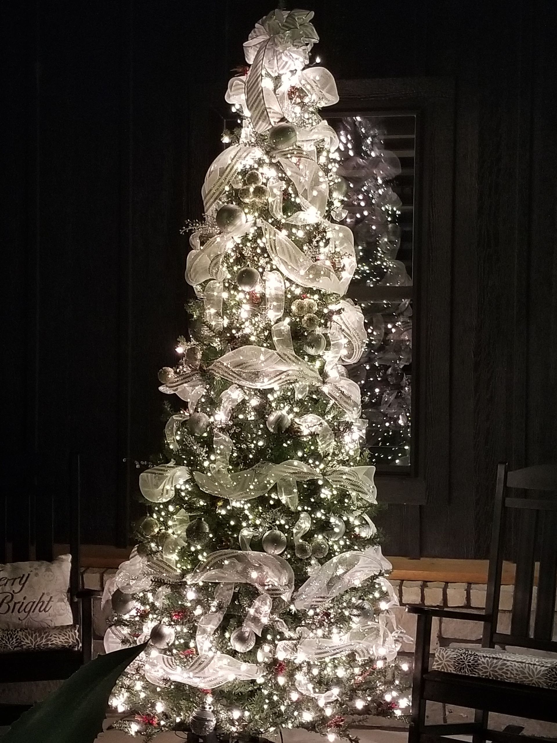 A Christmas tree lit up in a living room at night.