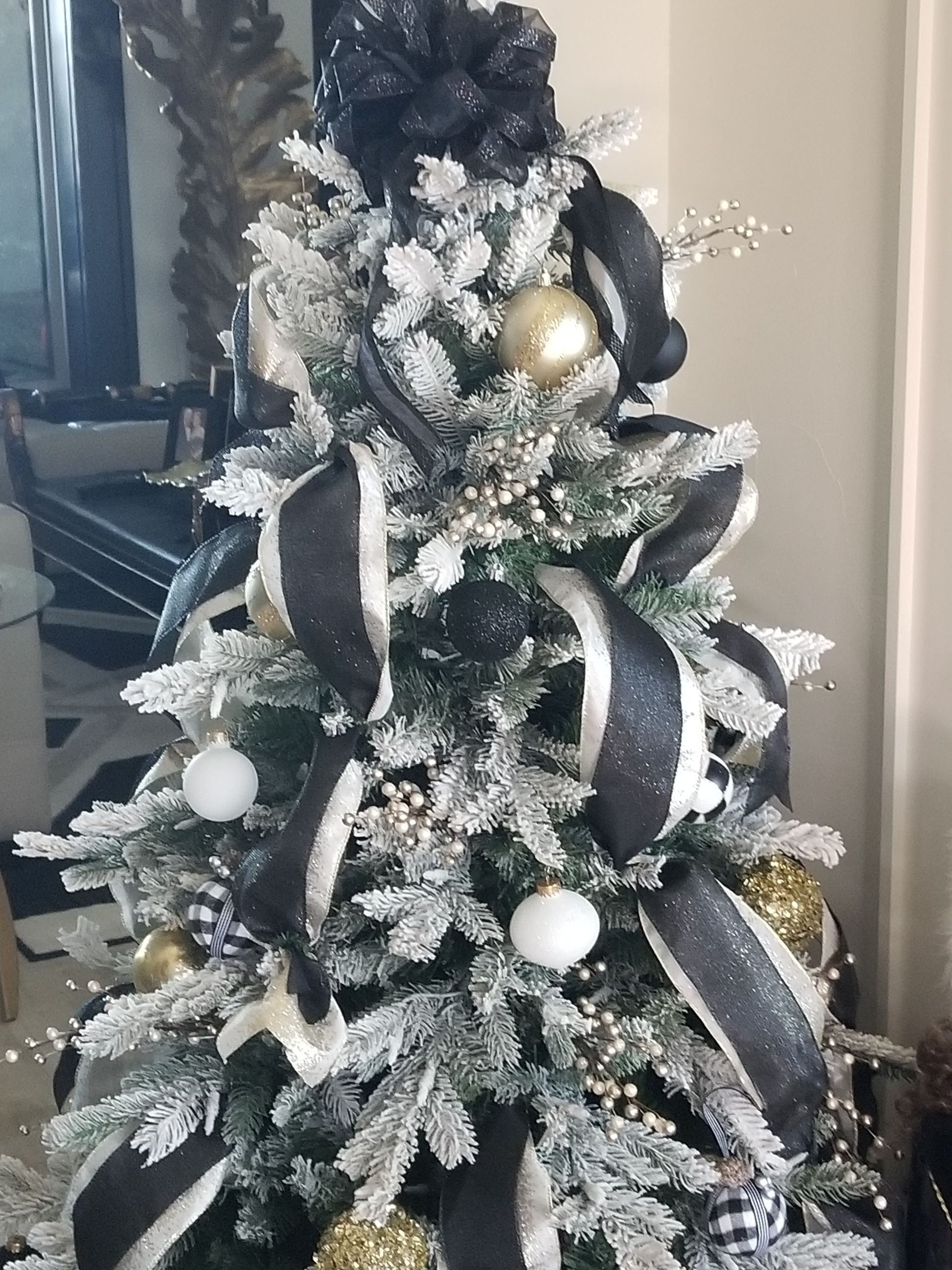 A flocked Christmas tree with ribbons and gold ornaments