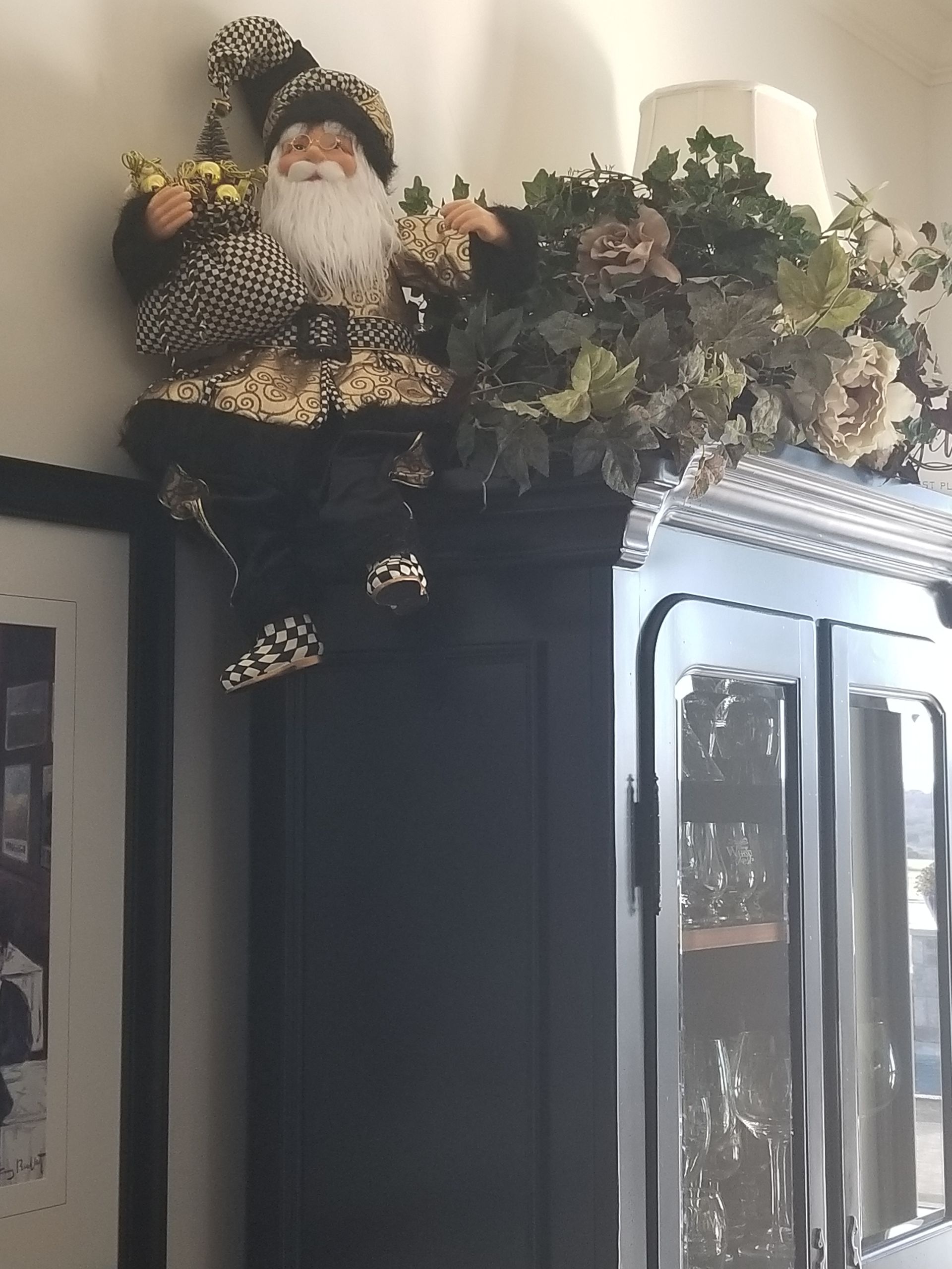 A Santa Claus figurine is sitting on top of a black cabinet