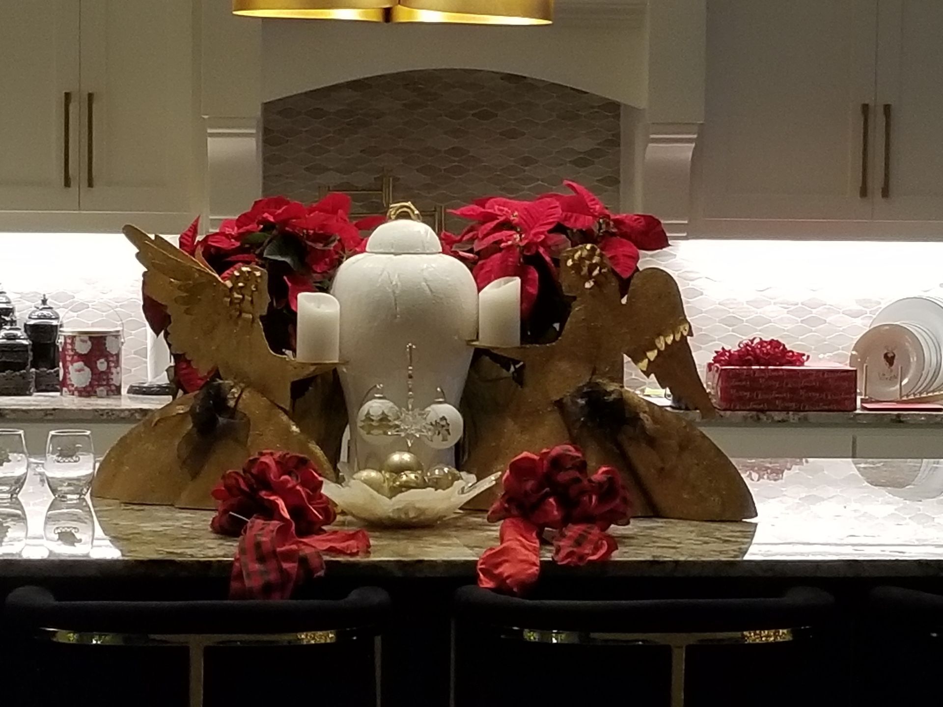 A kitchen counter with a vase of poinsettia flowers and candles on it.