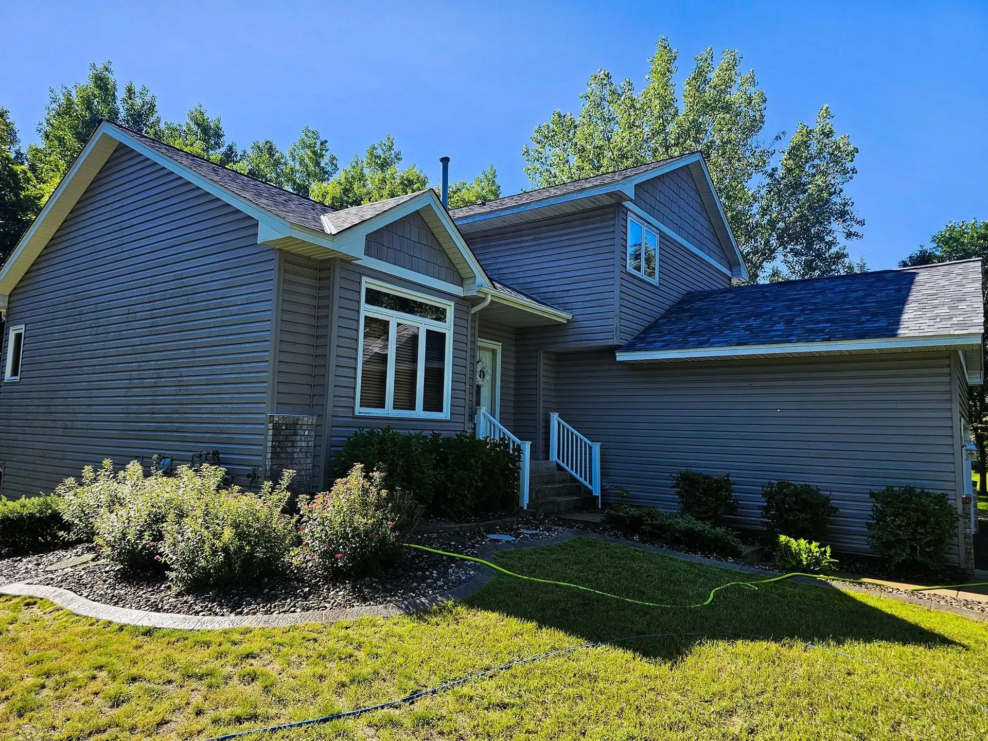 Gray house with blue roof, white trim, and a green lawn.