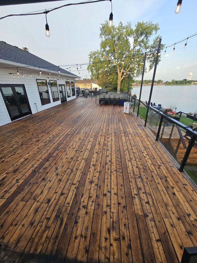 Workers cleaning a large, corrugated metal surface with pressure washers under a bright sky.