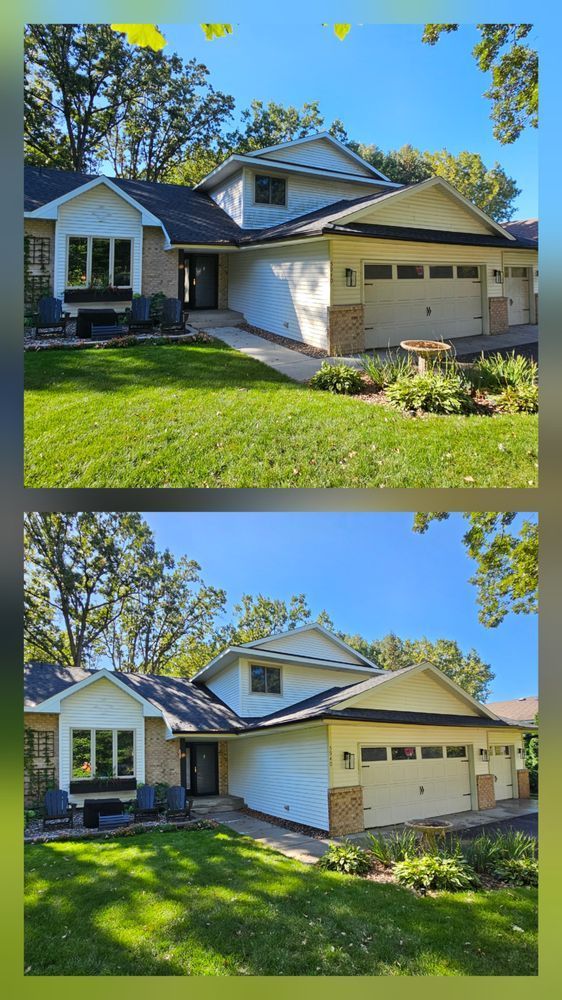 Two-story house with beige siding, brick accents, and a garage, on a grassy lawn under a blue sky.