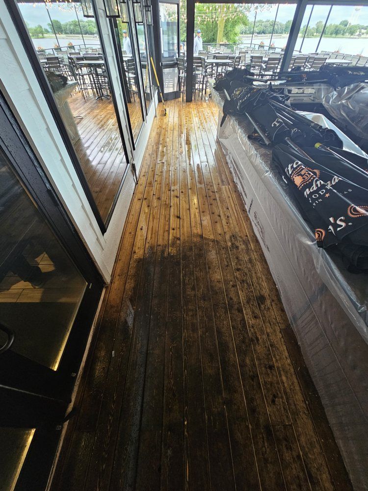 Wet wooden floor inside a restaurant with tables, chairs, and windows visible.