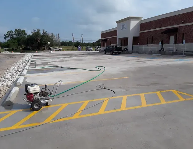 Parking lot striping in progress, with a yellow painted parking space in front of a brick building.