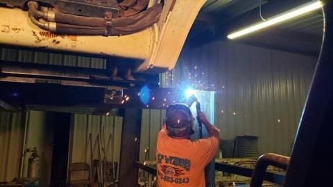 a man is welding a piece of metal in a garage .