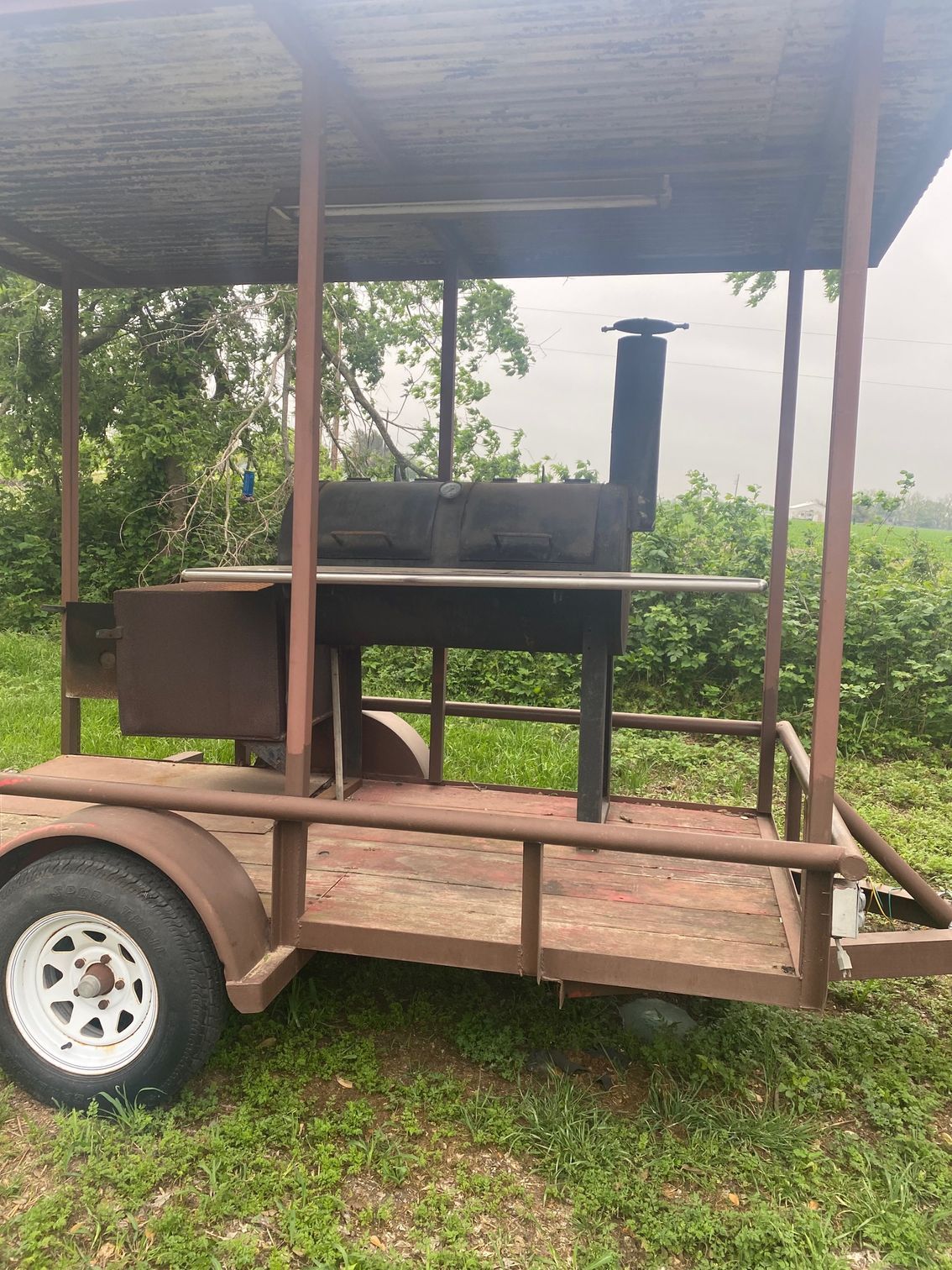 a trailer with a grill on it is parked in the grass .