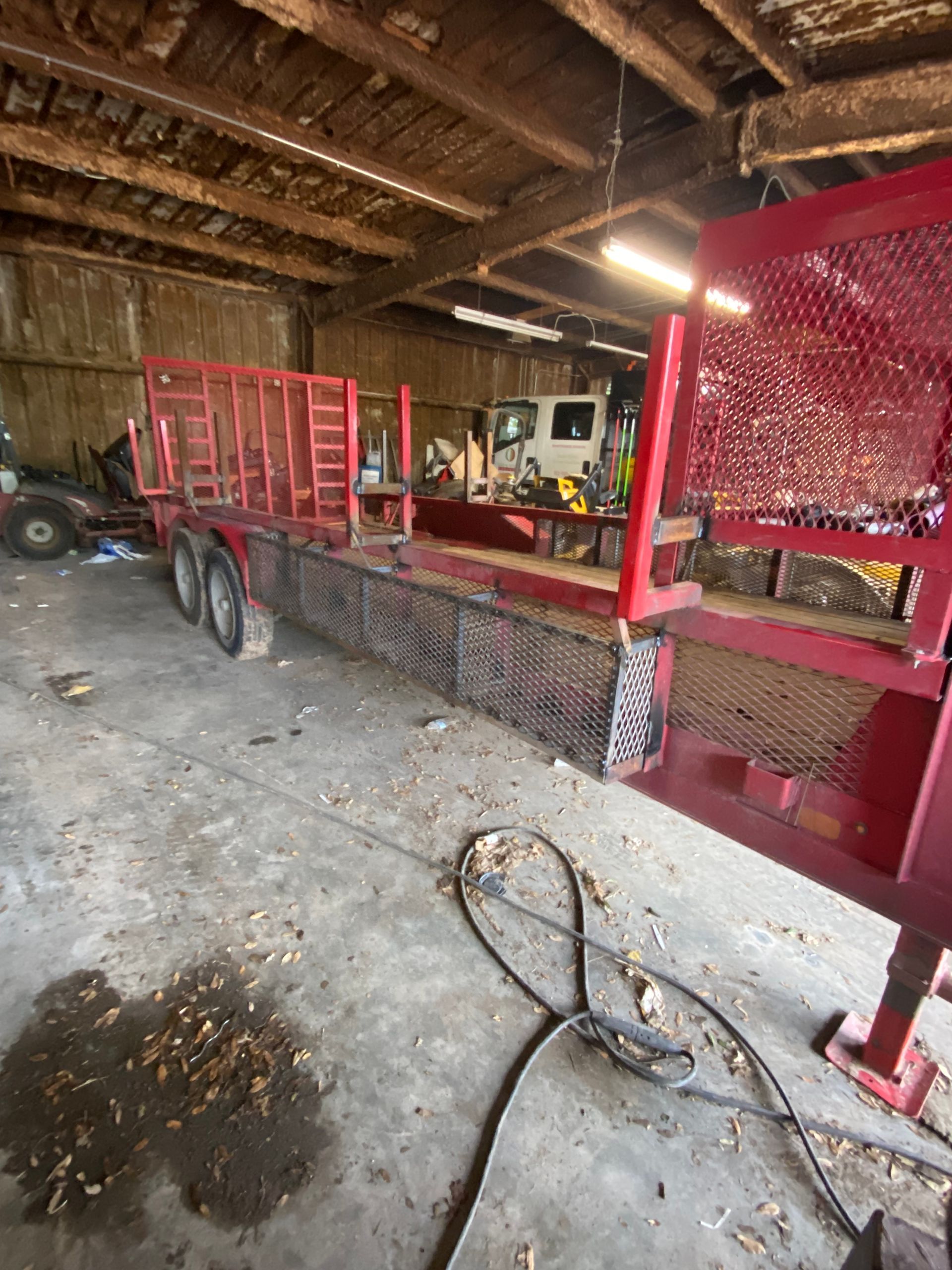 a red trailer is sitting in a garage next to a truck .