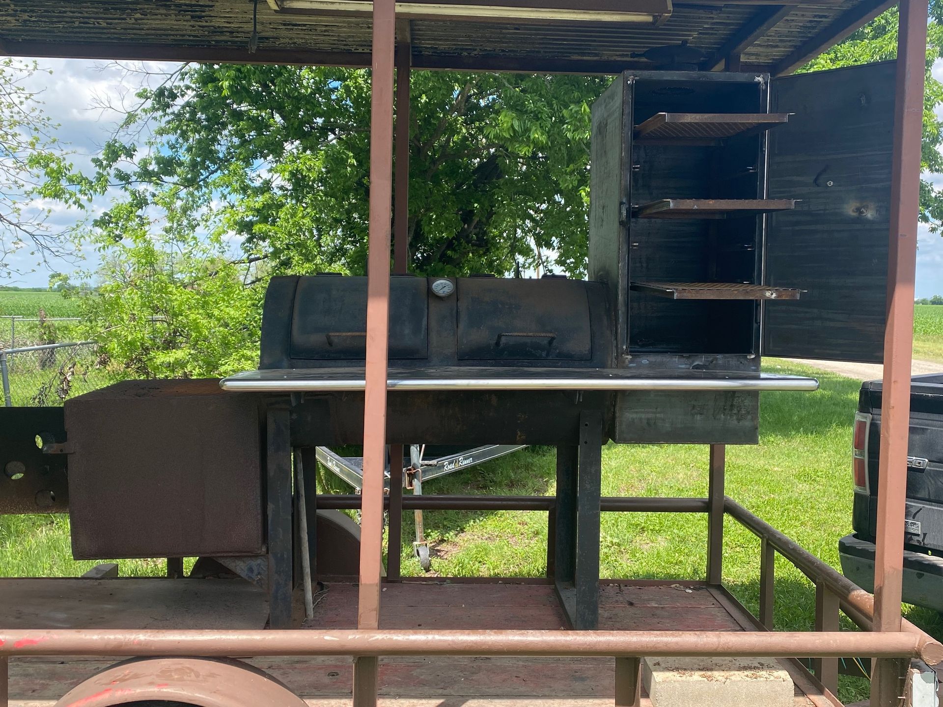 a bbq grill is sitting on top of a trailer with the doors open .