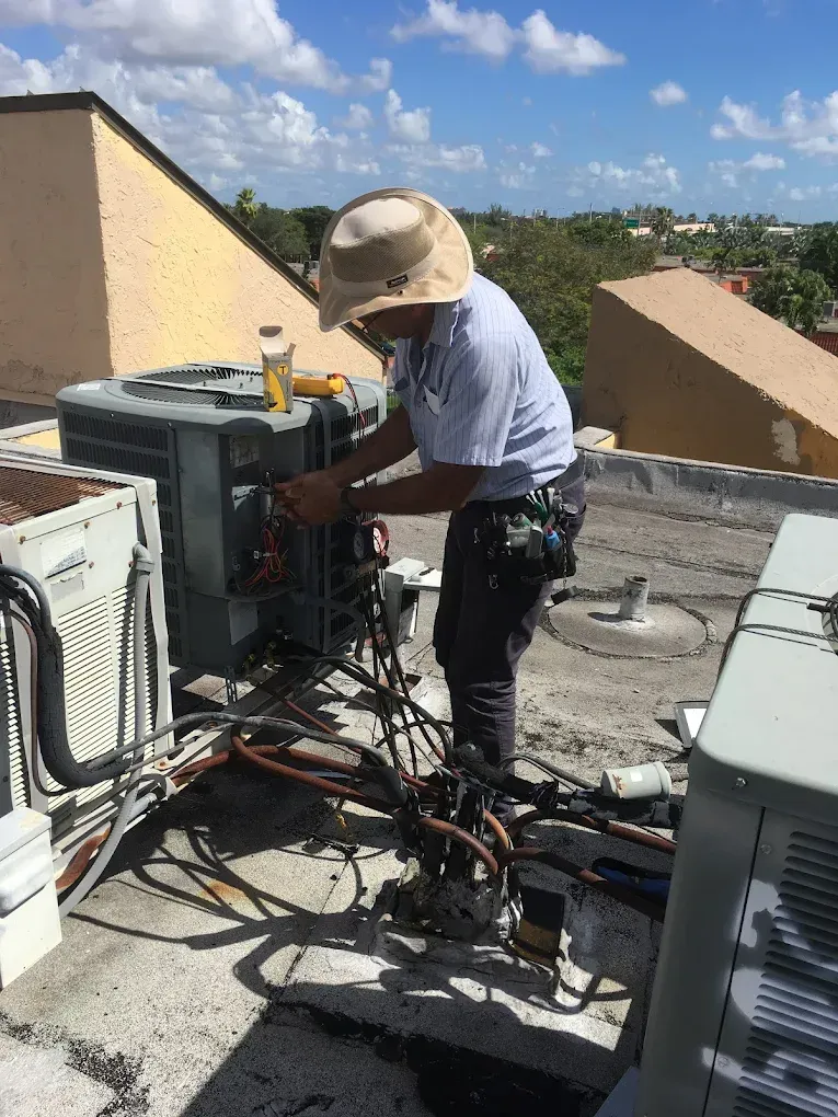 HVAC technician working on rooftop air conditioning unit, sunny day.