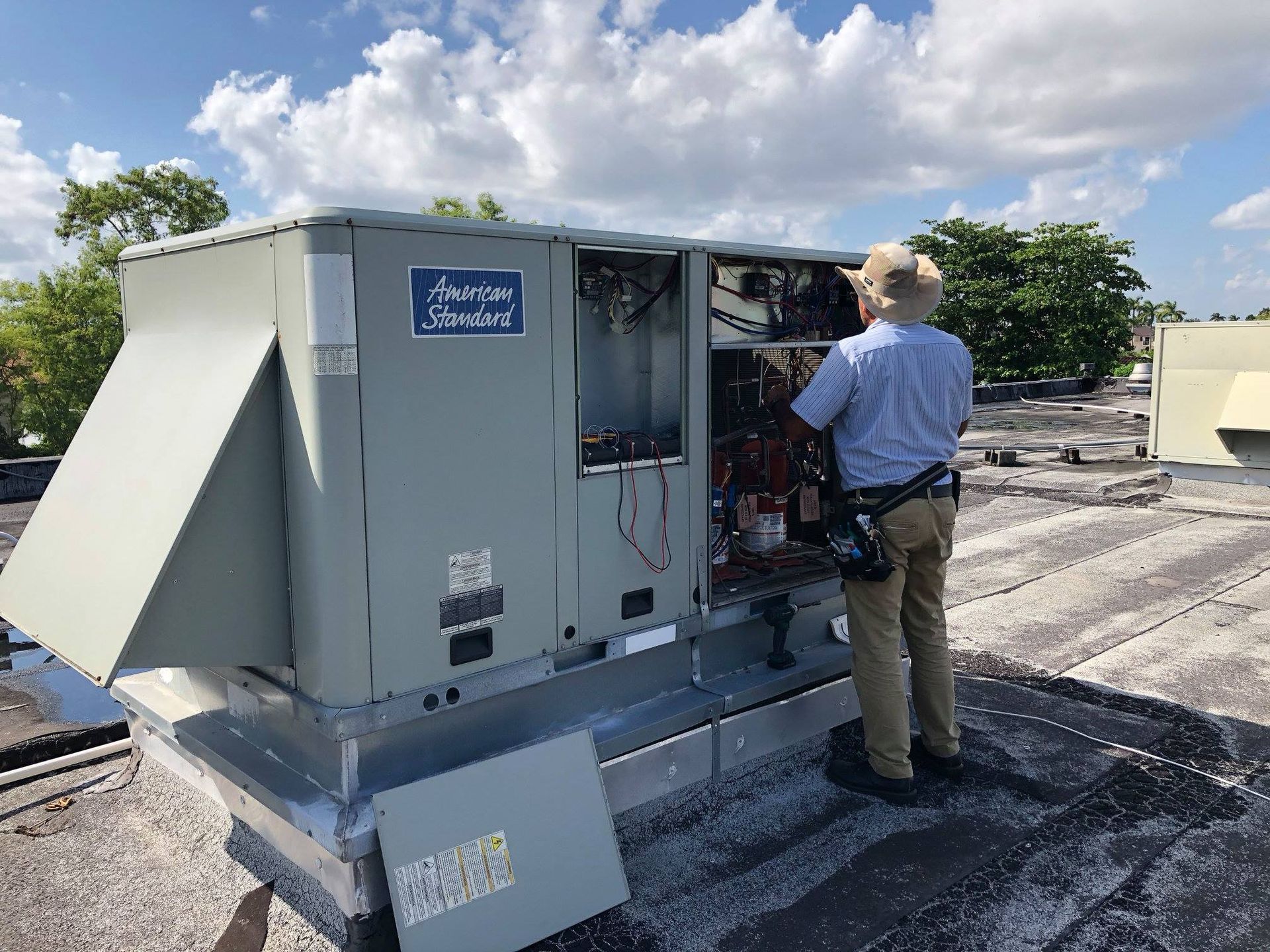 Woman in straw hat smiles, holding wine glass near a lake.