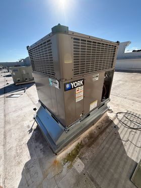 A York rooftop HVAC unit on a flat roof under a bright blue sky.
