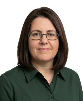A person with shoulder-length brown hair and glasses, wearing a navy blue blazer over a green top, against a white background.