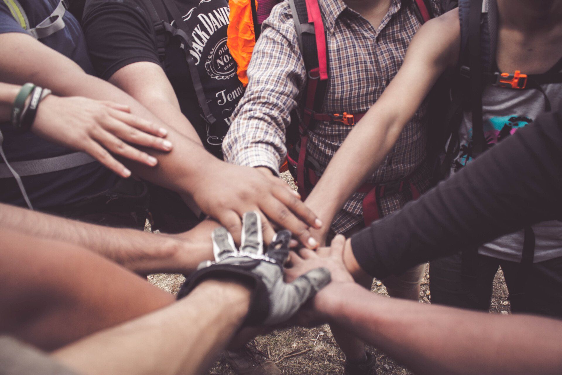 A close-up of a group of people placing their hands together in the center to signify unity and teamwork.