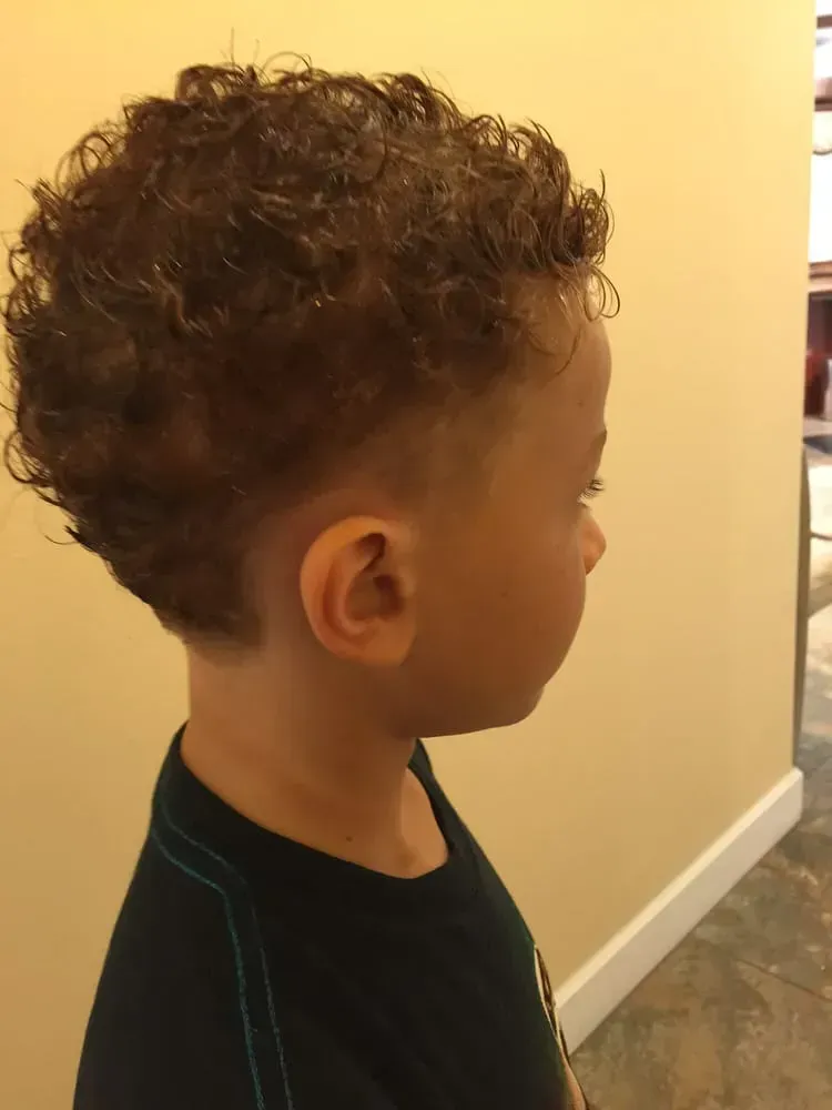 A young boy with curly hair is wearing a black shirt