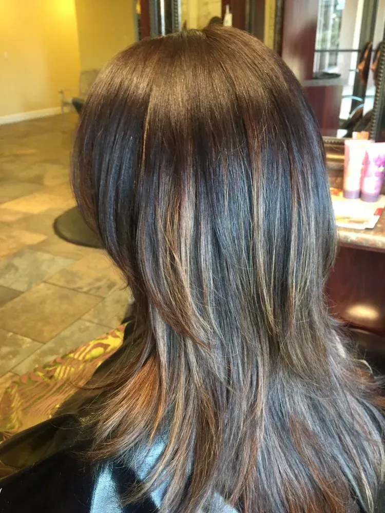 A woman with long brown hair is sitting in a chair in a salon.