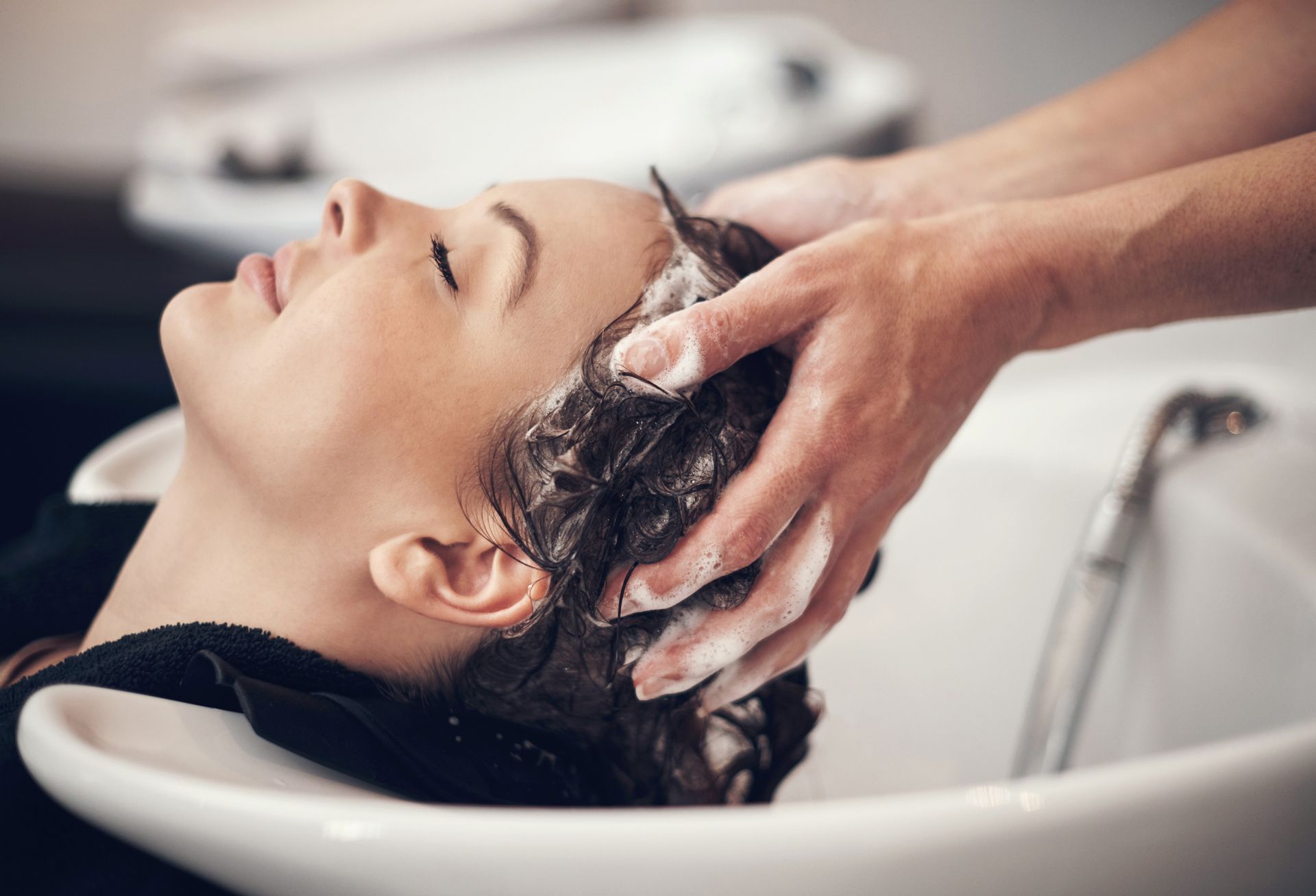 A woman is getting her hair washed in a sink at a salon.