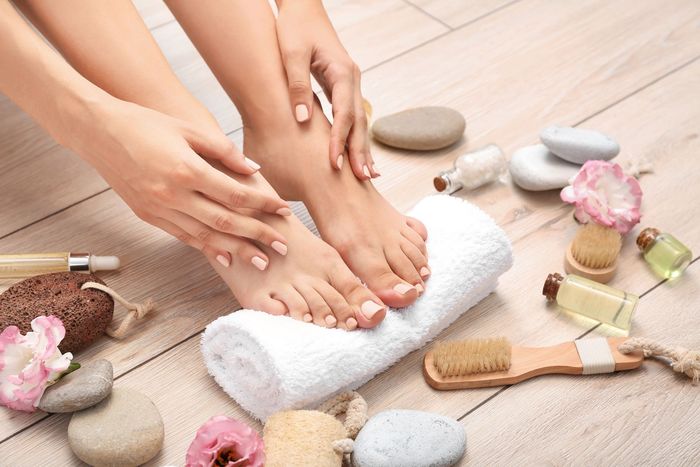 A woman is sitting on the floor with her feet on a towel.