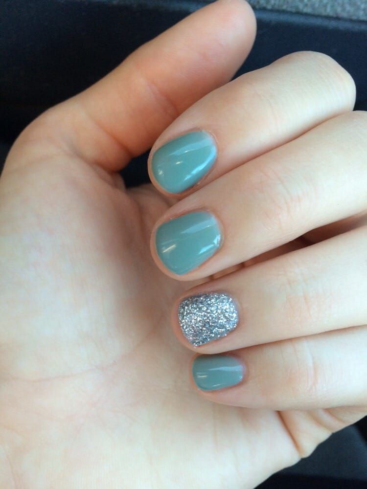 A close-up of a person's hand with blue and silver nails.