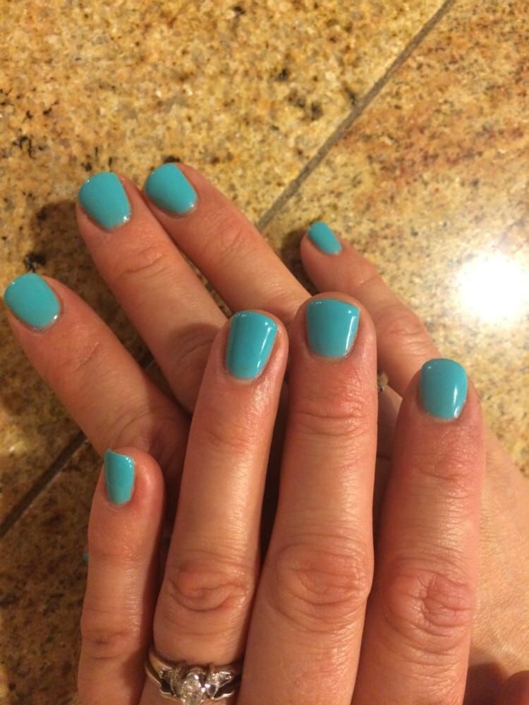 A close-up of a woman's hands with blue nails and a ring.