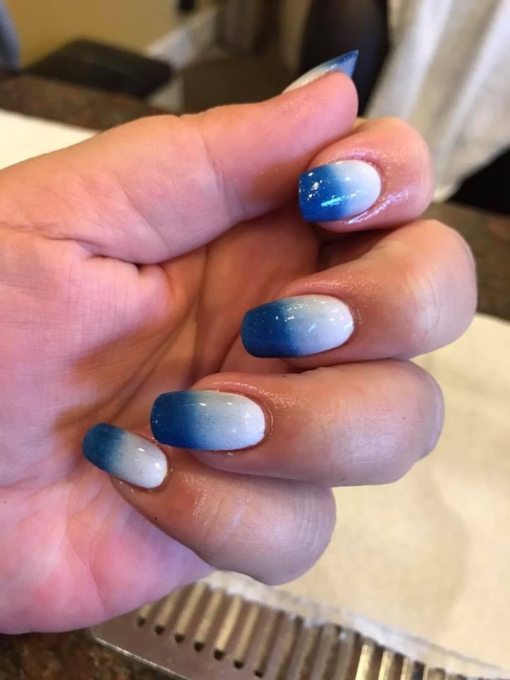A close-up of a person's hand with blue and white nails.