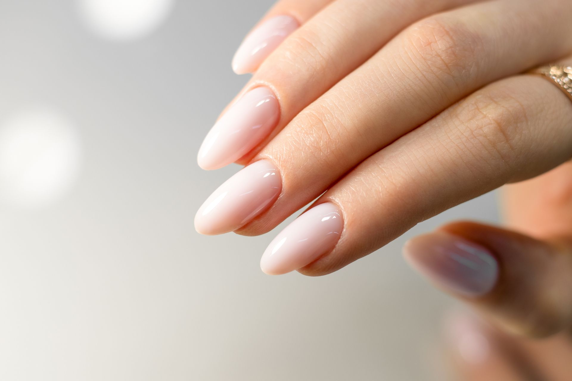 A close-up of a woman's hand with long nails and a ring on her finger.