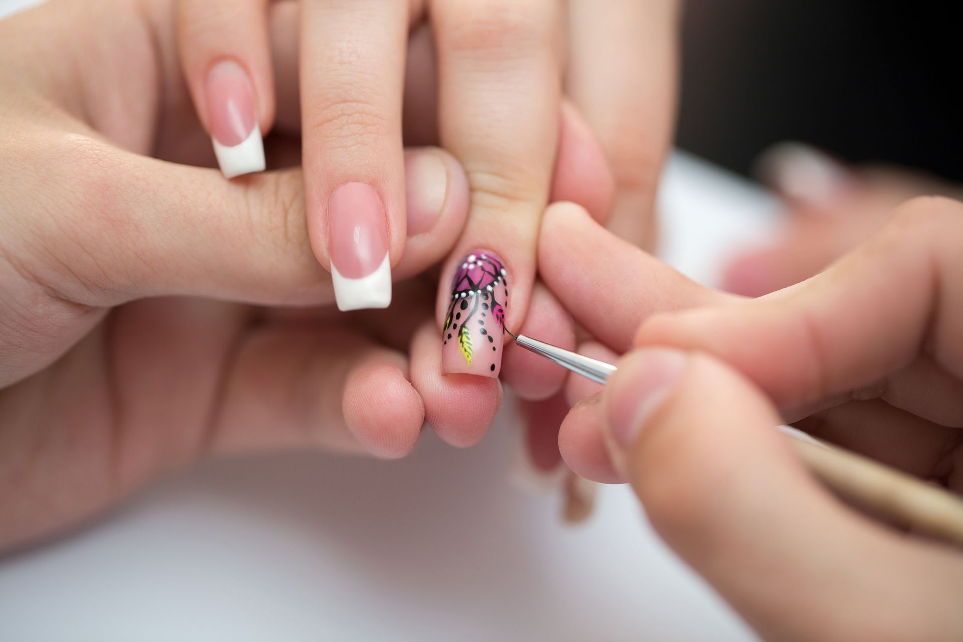 A woman is getting her nails painted by a nail artist.