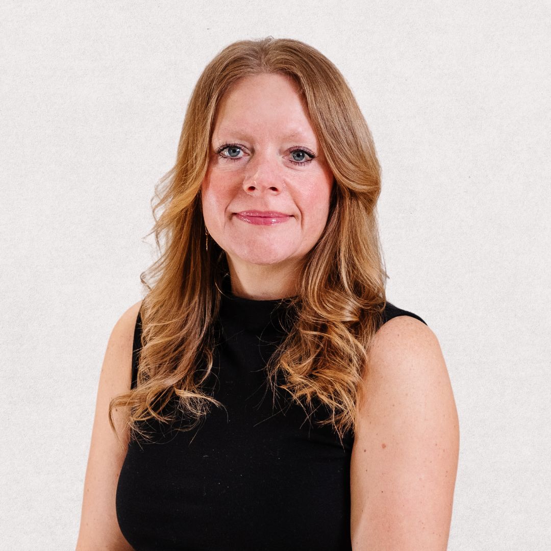 The woman is wearing a black top and smiling for the camera.