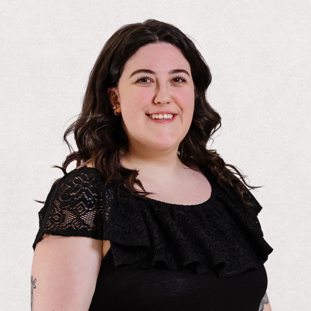 A woman in a black lace top is smiling for the camera