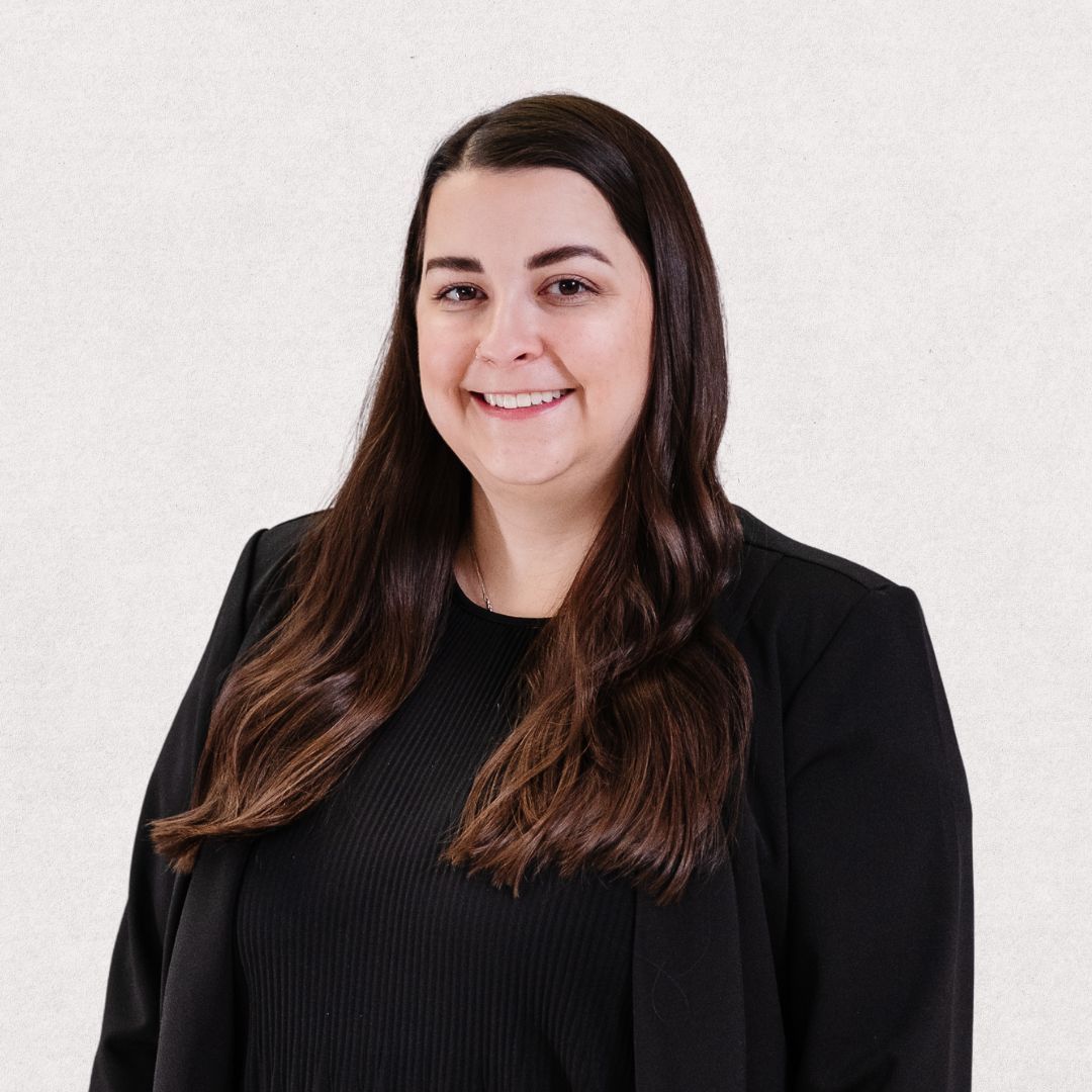 A woman wearing a black jacket and a black shirt is smiling for the camera.