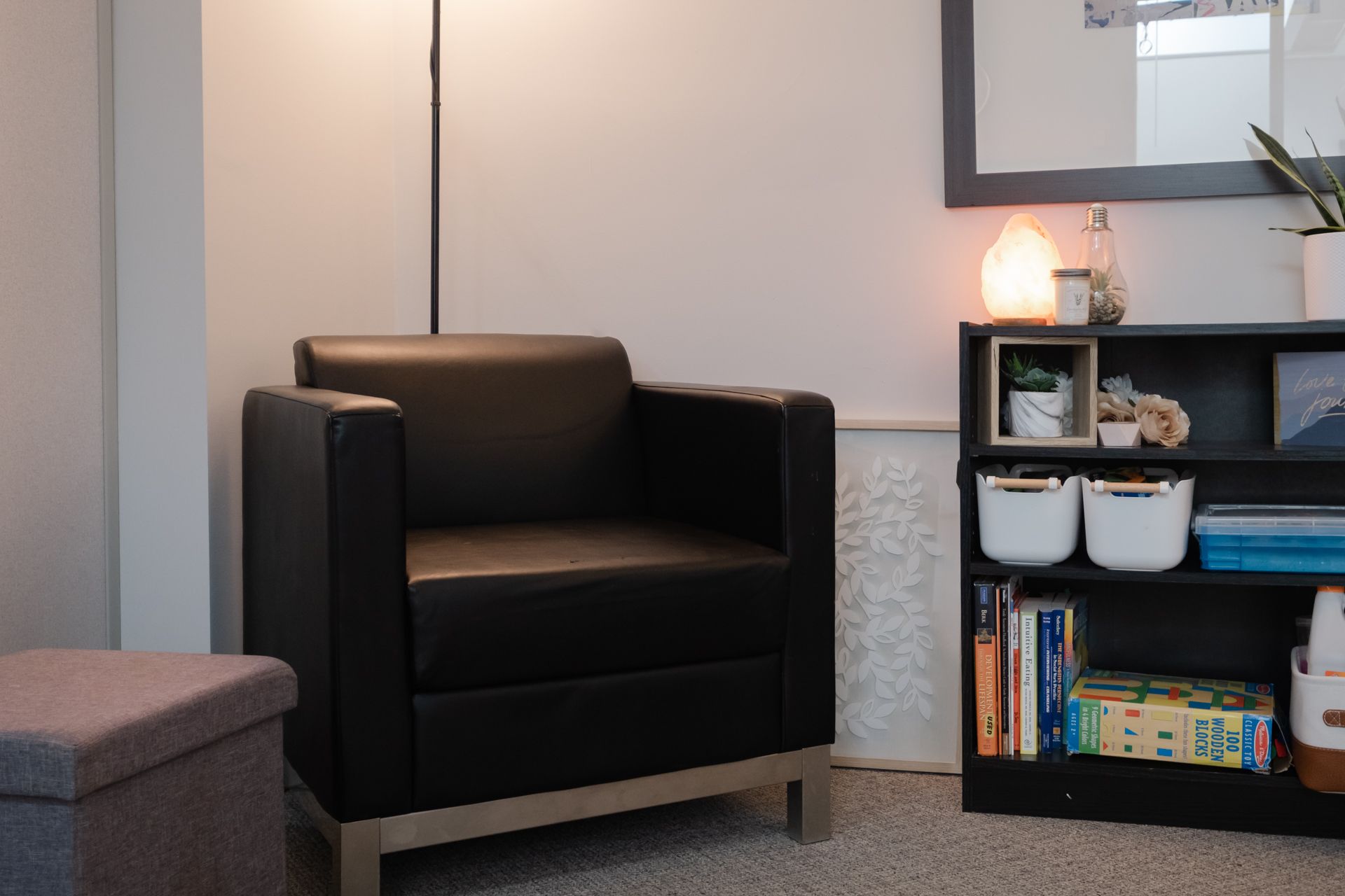 A black chair is sitting in a living room next to a bookshelf.